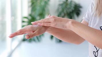 avvicinamento donna è mani idratante mani con crema su Monstera sfocato sfondo. mano massaggio. cosmetologia, mano cura, terme cosmetici, bellezza concetto. video