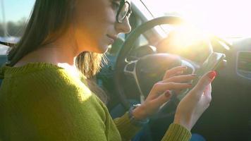 vrouw in bril gebruik makend van een smartphone in de auto video