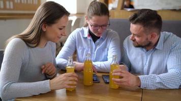 drei freunde sitzen im ein Cafe, trinken Saft und haben Spaß kommunizieren video