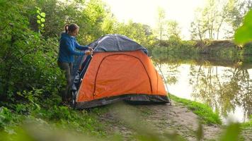 Woman is putting a tourist tent in the forest video