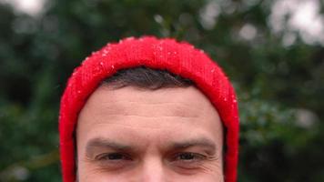 portrait de une homme dans une rouge casquette dans neigeux temps en plein air video