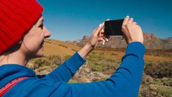 aktiva vandrare kvinna vandring på teide nationell parkera och gör Foto landskap på de smartphone. teneriffa, kanariefågel öar video