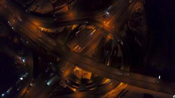 vertical parte superior abajo aéreo ver de tráfico en autopista intercambio a noche video