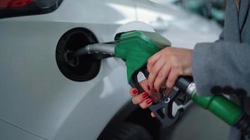 Woman inserts a fuel gun in a gas tank to refuel a car video