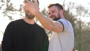 Young gay couple taking photo of themself on a film camera in the spring evening video