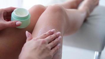 un mujer aplica crema a su piernas . mujer es utilizar de anticelulítico crema. hembra cuerpo cuidado. cosmetología, masaje, spa cosmético productos video