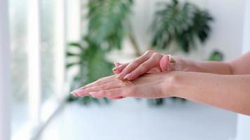 Close-up woman is hands with coffee massage scrub on monstera blurred background. Cosmetology, hand care, spa cosmetics, beauty concept. video