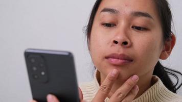 Close up of young woman squeezing pimples on her face. Problematic skin in dark-haired asian woman. Concept of skin problems and skin care. video