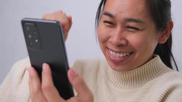 Portrait of happy woman enjoying success on mobile phone at home. Close-up of happy young woman reading good news on the phone. Surprised woman celebrating success on the phone. video