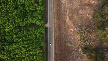 Aerial view of a road that cuts through a lush forest, on the other side is an area destroyed by humans for cultivation of mountain crops. Areas with dense smog and covered with PM2.5. Air pollution video
