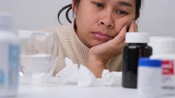 Unhealthy Asian woman in sweater blowing nose in disposable tissue. Allergy to dust, animal dander, cold, or viral infection. Healthy and medicine concept. video