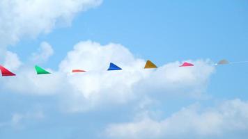 bunt klein Flaggen im das Himmel. winken klein bunt Flaggen hängend auf das Seil zum Ferien gegen Blau Himmel. video