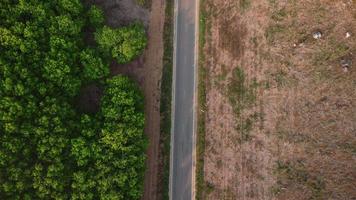 Aerial view of a road that cuts through a lush forest, on the other side is an area destroyed by humans for cultivation of mountain crops. Areas with dense smog and covered with PM2.5. Air pollution video