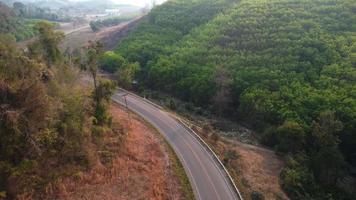 Aerial view of a road that cuts through a lush forest, on the other side is an area destroyed by humans for cultivation of mountain crops. Areas with dense smog and covered with PM2.5. Air pollution video