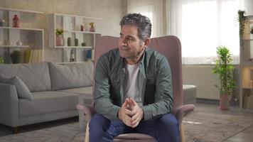 Worried mature man suffering from depression and loneliness not feeling well at home. Depressed and lonely mature man sitting on sofa at home thoughtful with depression mental health concept. video