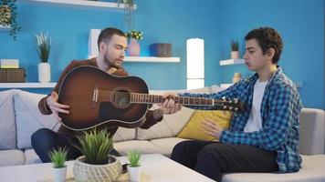 The cynical elder brother is teaching his younger brother to play the guitar. video