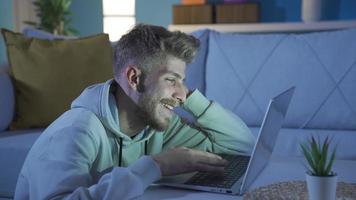 Happy and cute young man texting on laptop. Happy and cheerful young man in a good mood using laptop at home texting, browsing virtual world. video