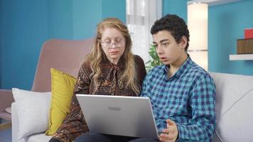 il ragazzo usi un' il computer portatile a casa e racconta il suo madre, chi è Guardando lui. giovane uomo mostrando qualcosa a partire dal il computer portatile per il suo madre. video