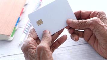 ouderen vrouw hand- Holding credit kaarten lezing informatie video