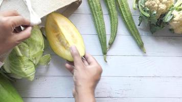 Man hand putting vegetables in a reusable bag wooden table video