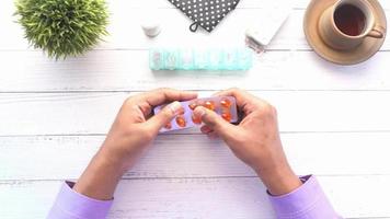 Man hand taking vitamin capsules from a blister pack, top down video