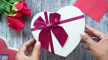 Top view of mans hand putting a gift box on wooden background . video