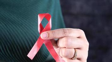 Hand holding red HIV ribbon with copy space video
