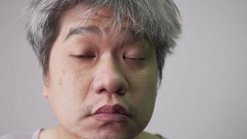 mayor asiático hombre cheques facial piel en el espejo. concepto de productos cosméticos y cuidado de la salud. video