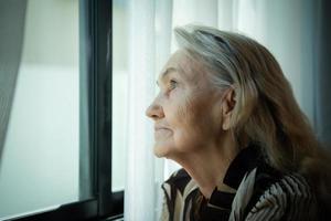 solitario antiguo mujer sentar y Mira fuera el ventana dónde el Mañana Dom brilla en. perder mi amado unos quien tener estado juntos para un largo tiempo, quien tener pasado lejos sin nunca viniendo atrás. foto