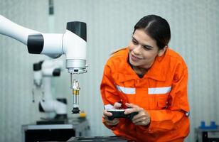 en un electrónico partes instalación, hembra ingenieros en el planta, inspeccionando y pruebas robótico manos usado en el producción de electrónico componentes foto