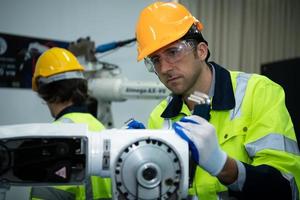 A big welding robot is being inspected and controlled by a robotics engineer. After the machine has been used for the specified amount of time. photo