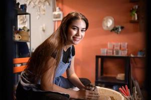 Pottery artist, Young female making a piece of clay molding calmly and meticulously In order to produce the most attractive work possible, photo