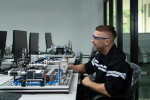 The robotic hand technology teacher is instructing new students on how to use electronic circuit boards and robotic hand commands for a variety of industrial applications. photo