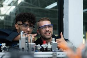 The robotic hand technology teacher is instructing new students on how to use electronic circuit boards and robotic hand commands for a variety of industrial applications. photo
