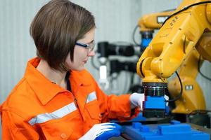 en un electrónico partes instalación, hembra ingenieros en el planta, inspeccionando y pruebas robótico manos usado en el producción de electrónico componentes foto