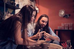 joven parejas ese disfrutar haciendo arcilla esculturas utilizando cerámica y ayudando uno otro a crear flor floreros fuera de arcilla foto