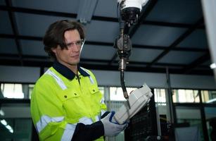 A big welding robot is being inspected and controlled by a robotics engineer. After the machine has been used for the specified amount of time. photo