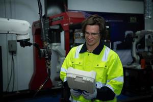 A big welding robot is being inspected and controlled by a robotics engineer. After the machine has been used for the specified amount of time. photo