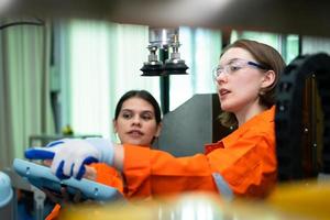 In an electronic parts facility, two female engineers In the plant, inspecting and testing robotic hands used in the production of electronic components. photo