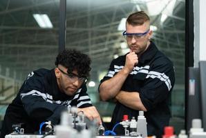 The robotic hand technology teacher is instructing new students on how to use electronic circuit boards and robotic hand commands for a variety of industrial applications. photo