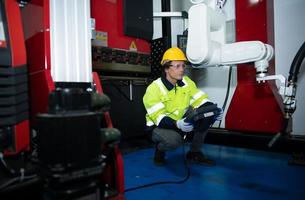 A big welding robot is being inspected and controlled by a robotics engineer. After the machine has been used for the specified amount of time. photo