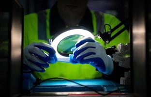 The technician must use bright lights and a magnifying glass to check the detail of the workpiece. the 3D printer's printout. photo