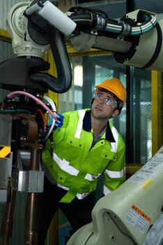 A big welding robot is being inspected and controlled by a robotics engineer. After the machine has been used for the specified amount of time. photo