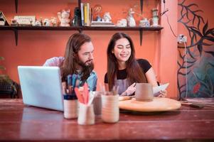 Two young entrepreneurs who own a pottery business. We are discussing the container that the customer wants to be molded. to be used to decorate the house photo