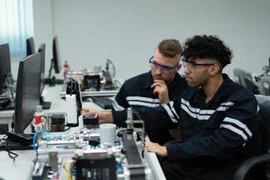 The robotic hand technology teacher is instructing new students on how to use electronic circuit boards and robotic hand commands for a variety of industrial applications. photo