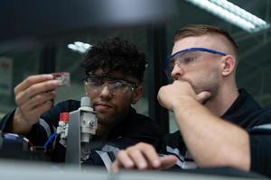 el robótico mano tecnología profesor es instruyendo nuevo estudiantes en cómo a utilizar electrónico circuito tableros y robótico mano comandos para un variedad de industrial aplicaciones foto