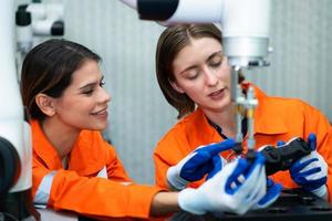 In an electronic parts facility, two female engineers In the plant, inspecting and testing robotic hands used in the production of electronic components. photo