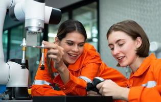 In an electronic parts facility, two female engineers In the plant, inspecting and testing robotic hands used in the production of electronic components. photo