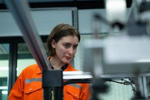 joven mujer en un electrónico partes fábrica utilizando un producción línea controlador y son recomendando colegas a utilizar esta herramienta. foto