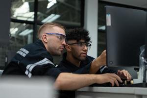 The robotic hand technology teacher is instructing new students on how to use electronic circuit boards and robotic hand commands for a variety of industrial applications. photo